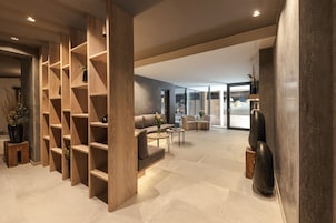 A modern living area with wooden shelving, a sofa, a coffee table, and a large window.