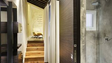 A modern interior with a wooden staircase, a glass shower enclosure, and a wall with a motivational quote.