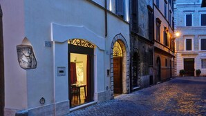 A cobblestone street with a building featuring an ornate entrance and a lion sculpture. - Relais Orso (Rome)