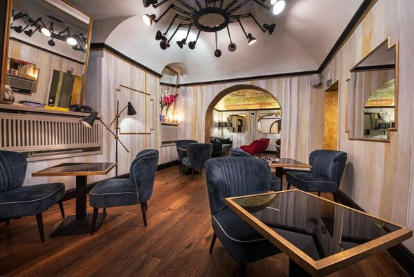 Un intérieur moderne avec un plancher en bois, des fauteuils rembourrés bleu foncé, une table en verre et un plafond doté de nombreux spots.