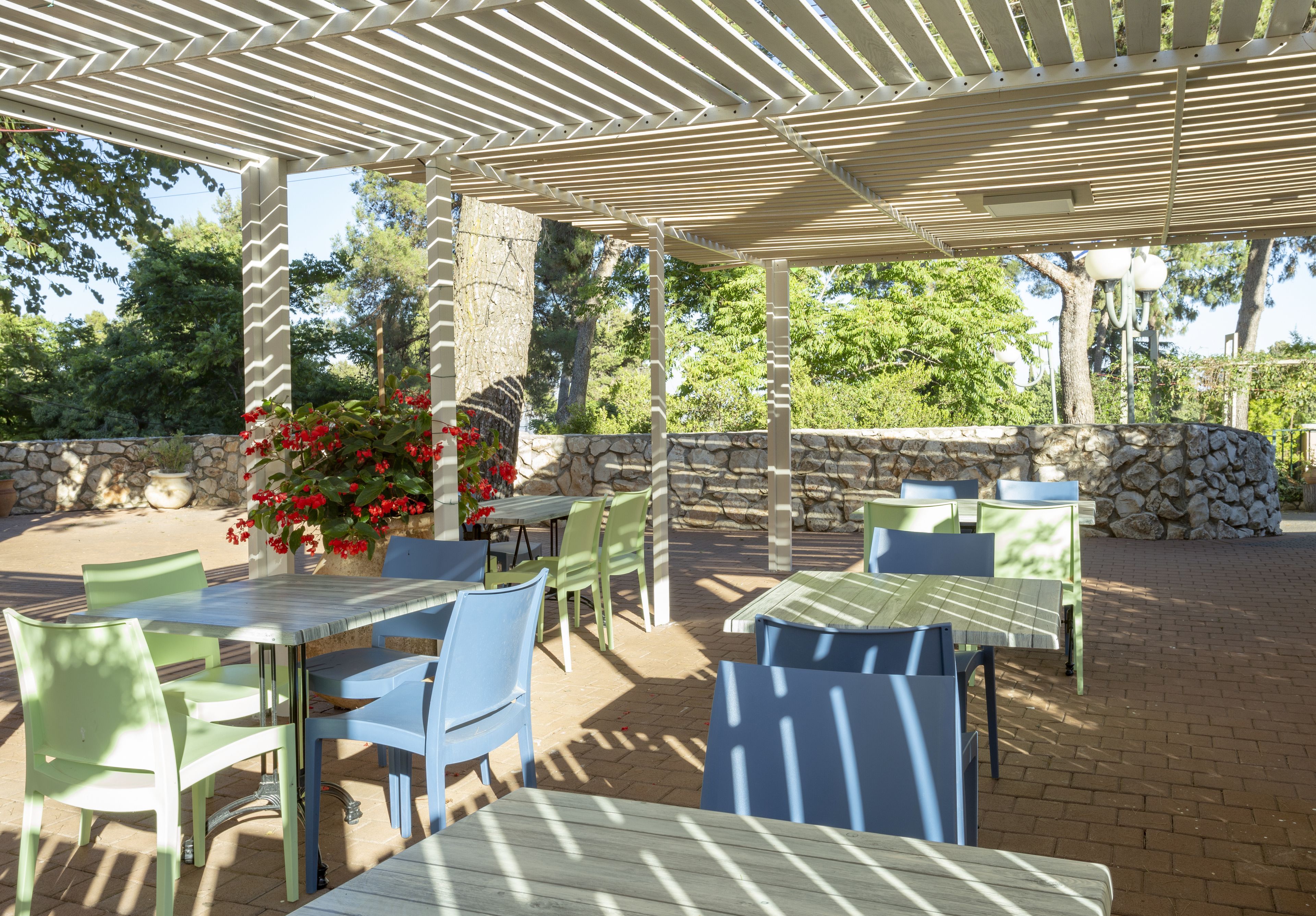 An outdoor patio with tables and chairs, stone walls, and a pergola.