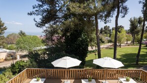 Una terraza de madera con dos mesas y sillas, cada una con un parasol blanco.