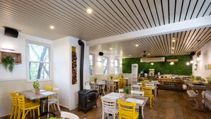 Un restaurante acogedor con mesas y sillas de madera, una chimenea y una pared verde.