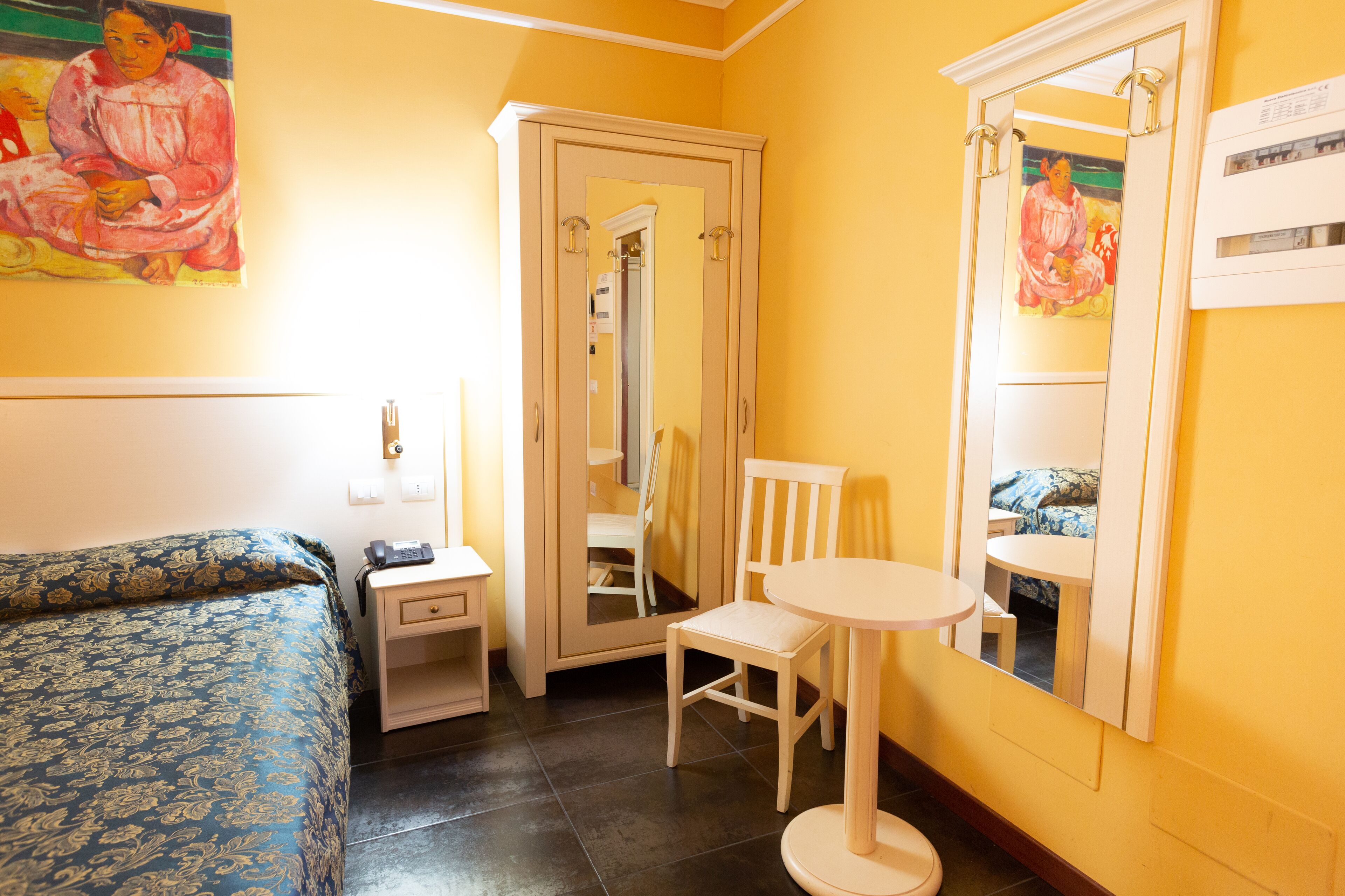 Ein Hotelzimmer mit Bett, Nachttisch, Stuhl und einem kleinen runden Tisch.