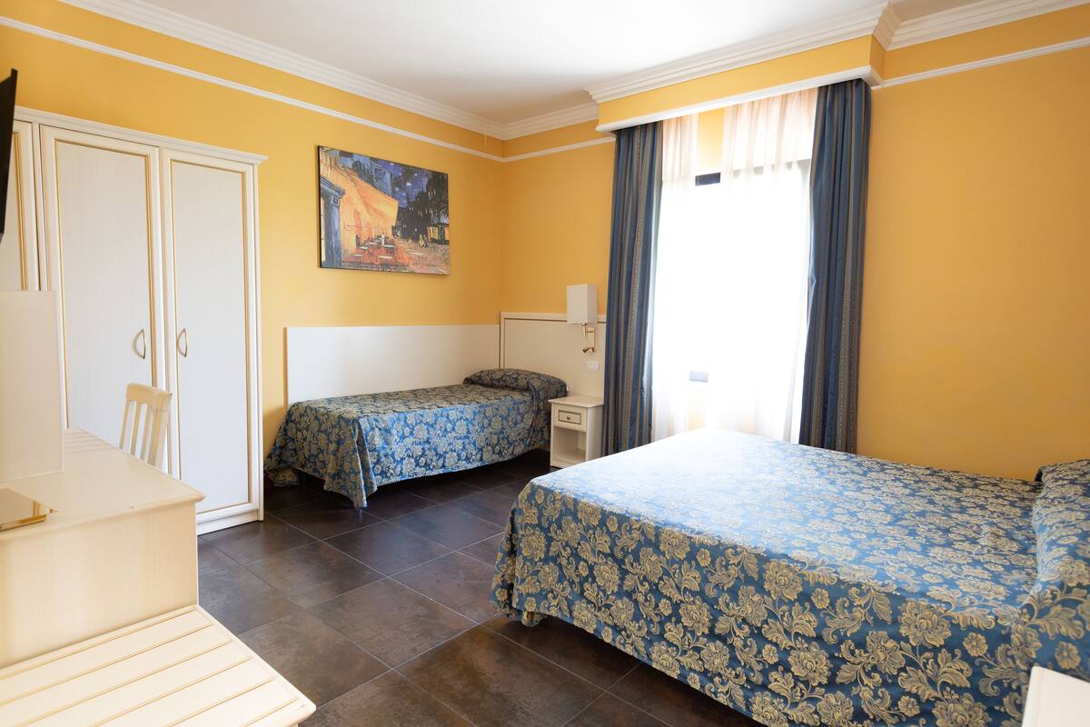 Ein Hotelzimmer mit zwei Betten, einem Schreibtisch, einem Stuhl und einem Kleiderschrank.