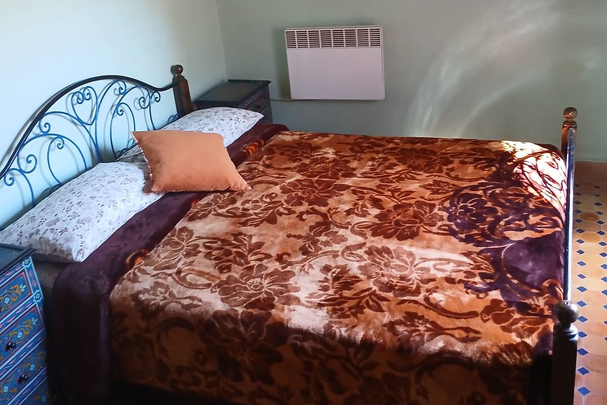 A bedroom with a bed, a dresser, a mirror, and a radiator.