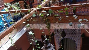 A multi-level interior with ornate tile work, a hanging plant, and a traditional-style lamp. - Riad Idrissi (Meknes)