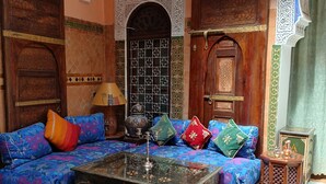 A traditional Moroccan interior with a patterned sofa, a coffee table, and a decorative lamp. - Riad Idrissi (Meknes)