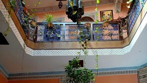 A traditional Moroccan interior with a central courtyard, ornate tile work, and a hanging plant. - Riad Idrissi (Meknes)