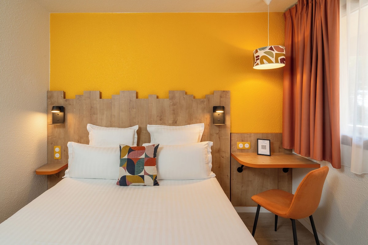 Ein Hotelzimmer mit Bett, Schreibtisch und Stuhl.