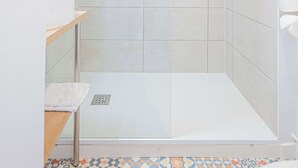 Ducha con puerta de vidrio, lavamanos y retrete.