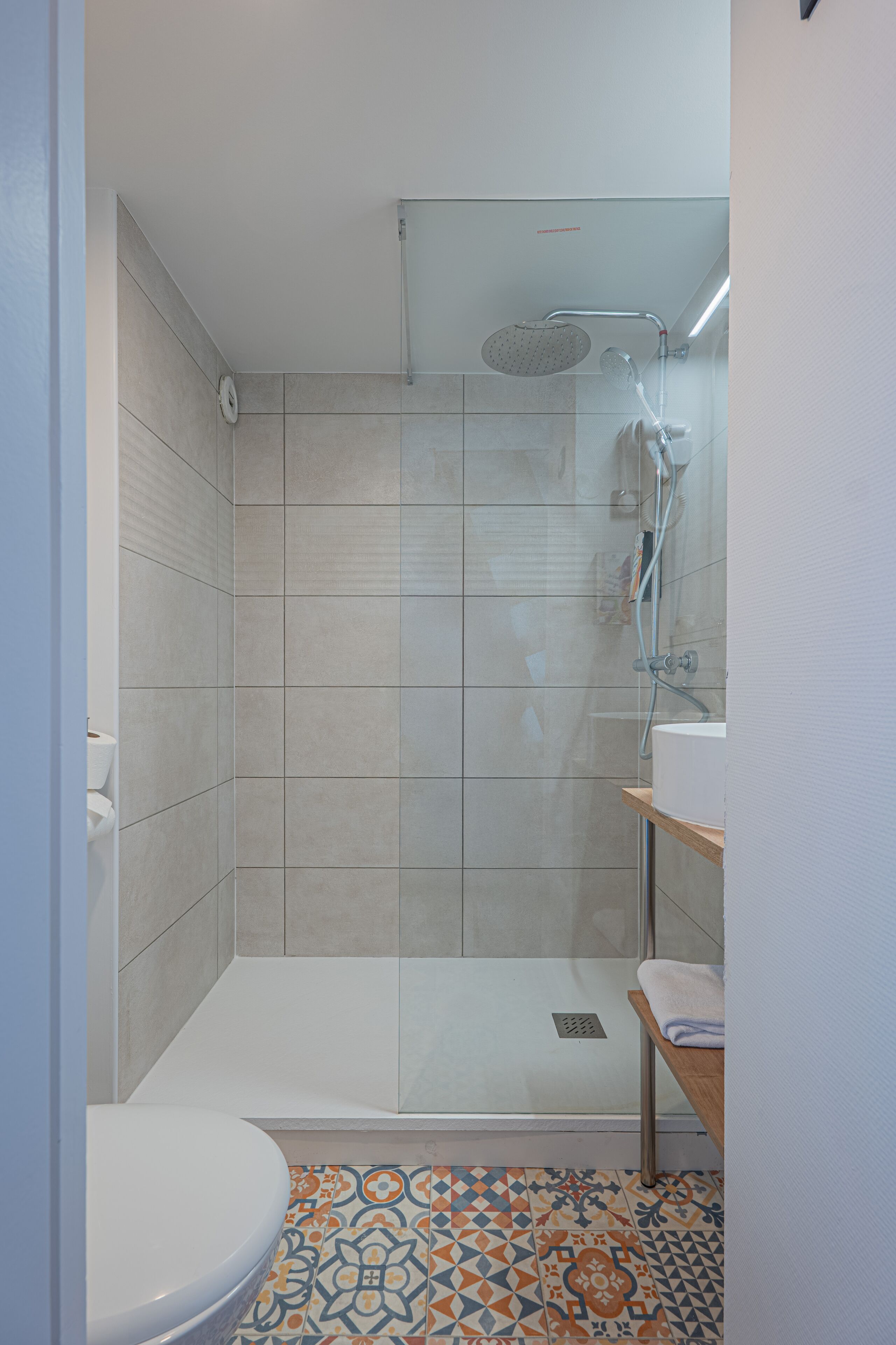 Een moderne badkamer met douche, toilet en wastafel.