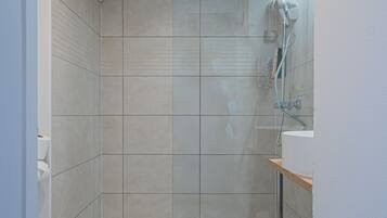 Een moderne badkamer met douche, toilet en wastafel.