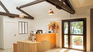 A reception area with a wooden desk, a large window, and a hanging flower arrangement.