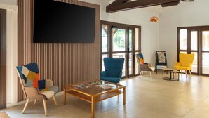 A modern interior with a large TV, a wooden coffee table, and two chairs with colorful upholstery.