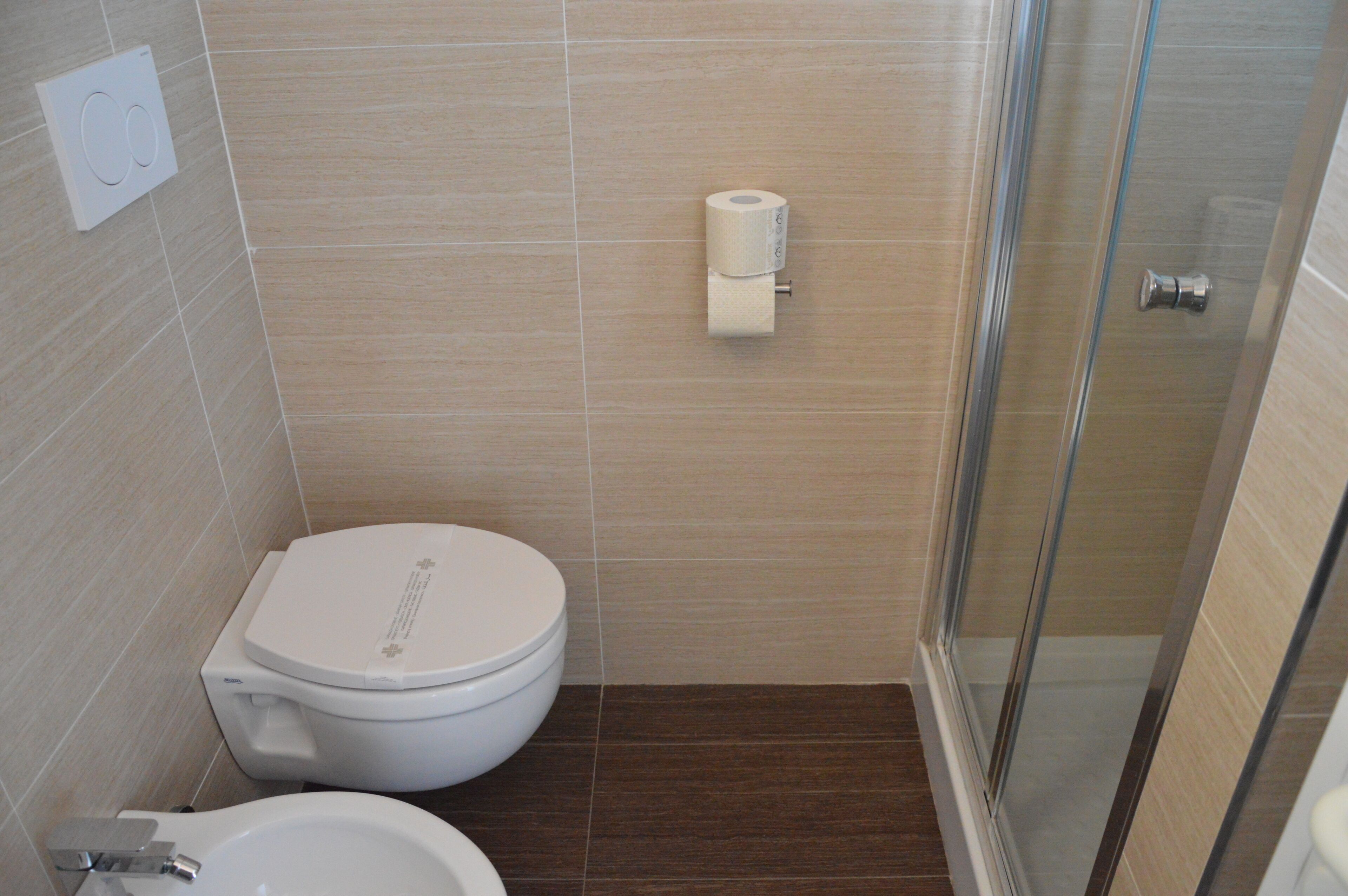 A bathroom with a toilet, bidet, and shower.