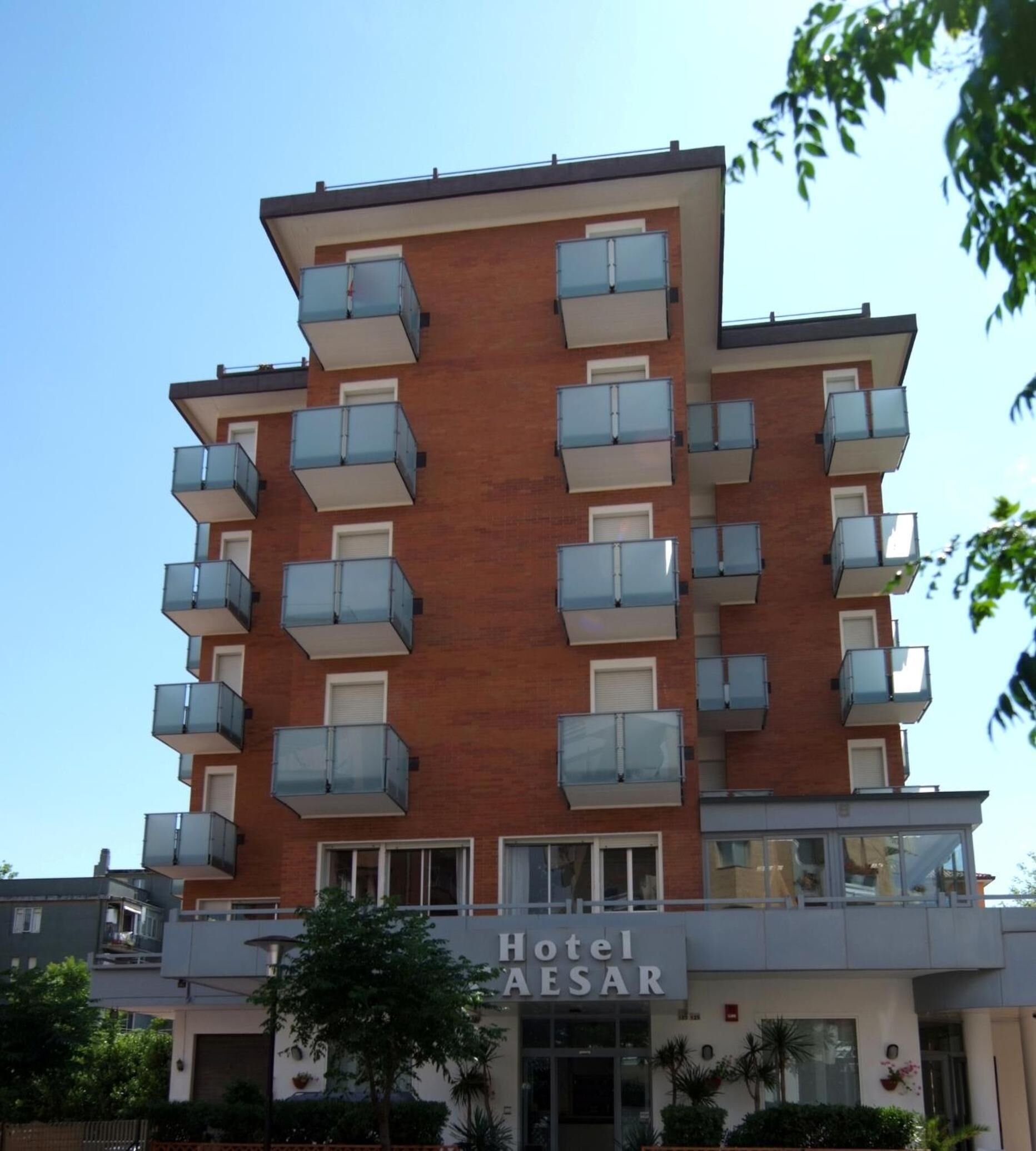 Un hotel moderno a più piani, con balconi su ogni piano e un cartello con la scritta 'Hotel Aesar'.