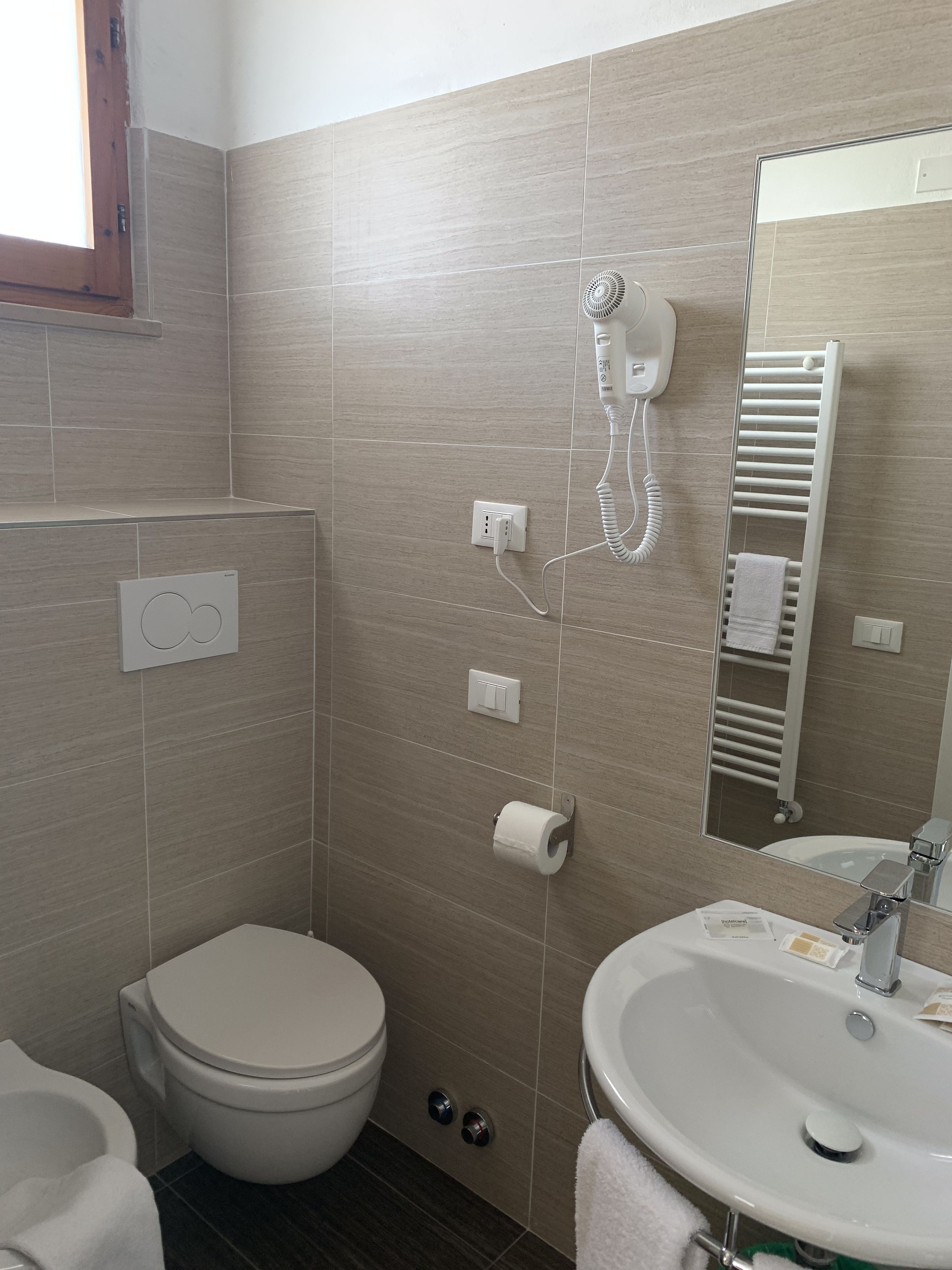 A bathroom with a toilet, sink, and a towel rack.