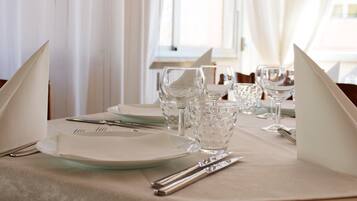 Uma mesa posta para refeição, com pratos, talheres e copos.