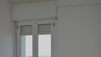 Een kamer met twee bedden en een schuifdeur naar een balkon met uitzicht op het strand.
