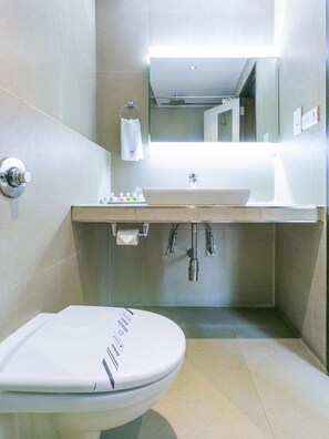 Ein modernes Badezimmer mit einer weißen Toilette, einem Waschbecken mit Spiegel darüber und einem Handtuch an einem Halter.