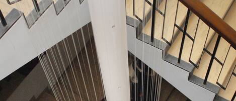 A multi-level interior with wooden flooring, metal railings, and a glass barrier.