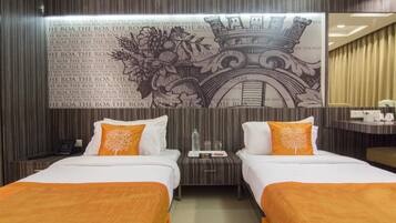 Habitación de hotel con dos camas, una mesita de noche, un espejo y un muro decorativo con una frase repetida.
