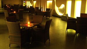 A dimly lit restaurant with wicker furniture and candles. - The Roa (Mumbai)