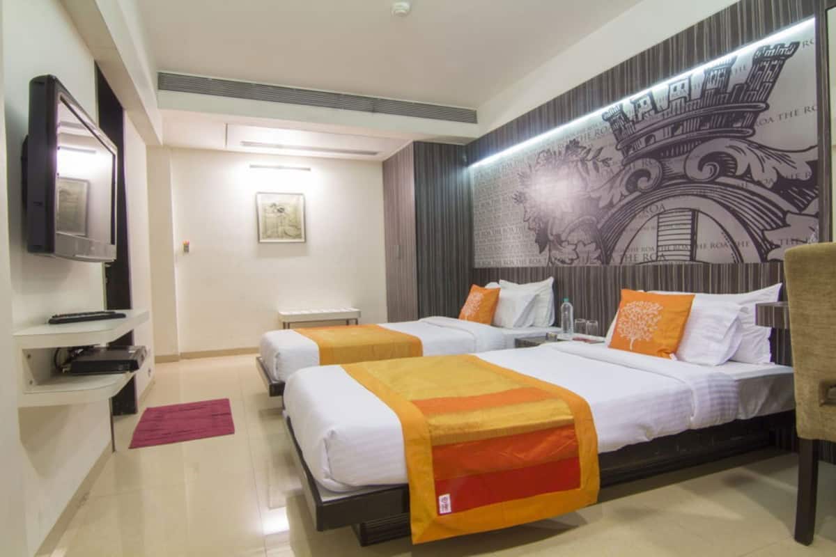 Habitación de hotel con dos camas, televisión, una mesita y un mural decorativo en la pared.