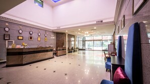 A hotel lobby with a reception desk, seating area, and a view of the street through large windows. - Formosa Corridor Hotel (Taichung)