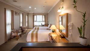 A hotel room with two beds, a desk, chairs, a mirror, a lamp, a potted plant, and a phone. - Formosa Corridor Hotel (Taichung)