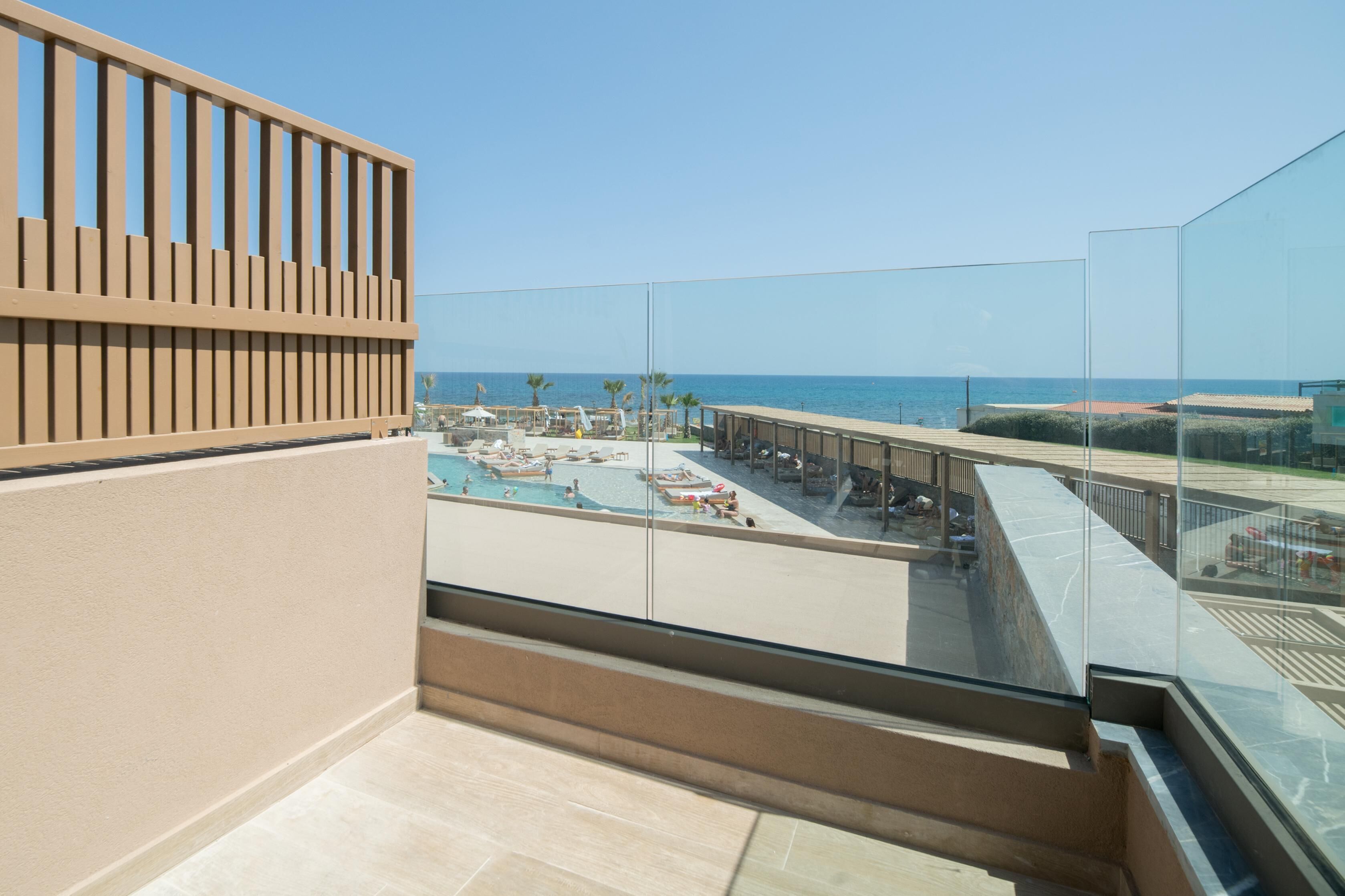 A balcony with a view of a pool area and the sea.