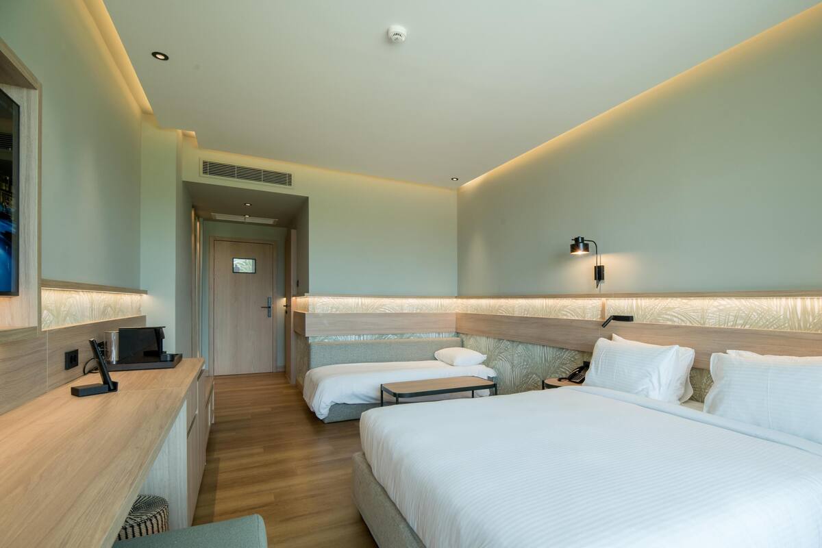 Une chambre d’hôtel avec un grand lit, un lit plus petit, un bureau et une table de chevet.