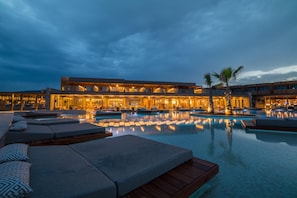 A hotel with a large outdoor pool, lounge areas, and a well-lit building facade. - Senseana Sea Side Resort & Aquadventure - All Inclusive (Hersonissos)