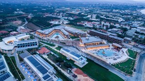 Vista aérea de um complexo hoteleiro com vários edifícios, piscina e painéis solares.