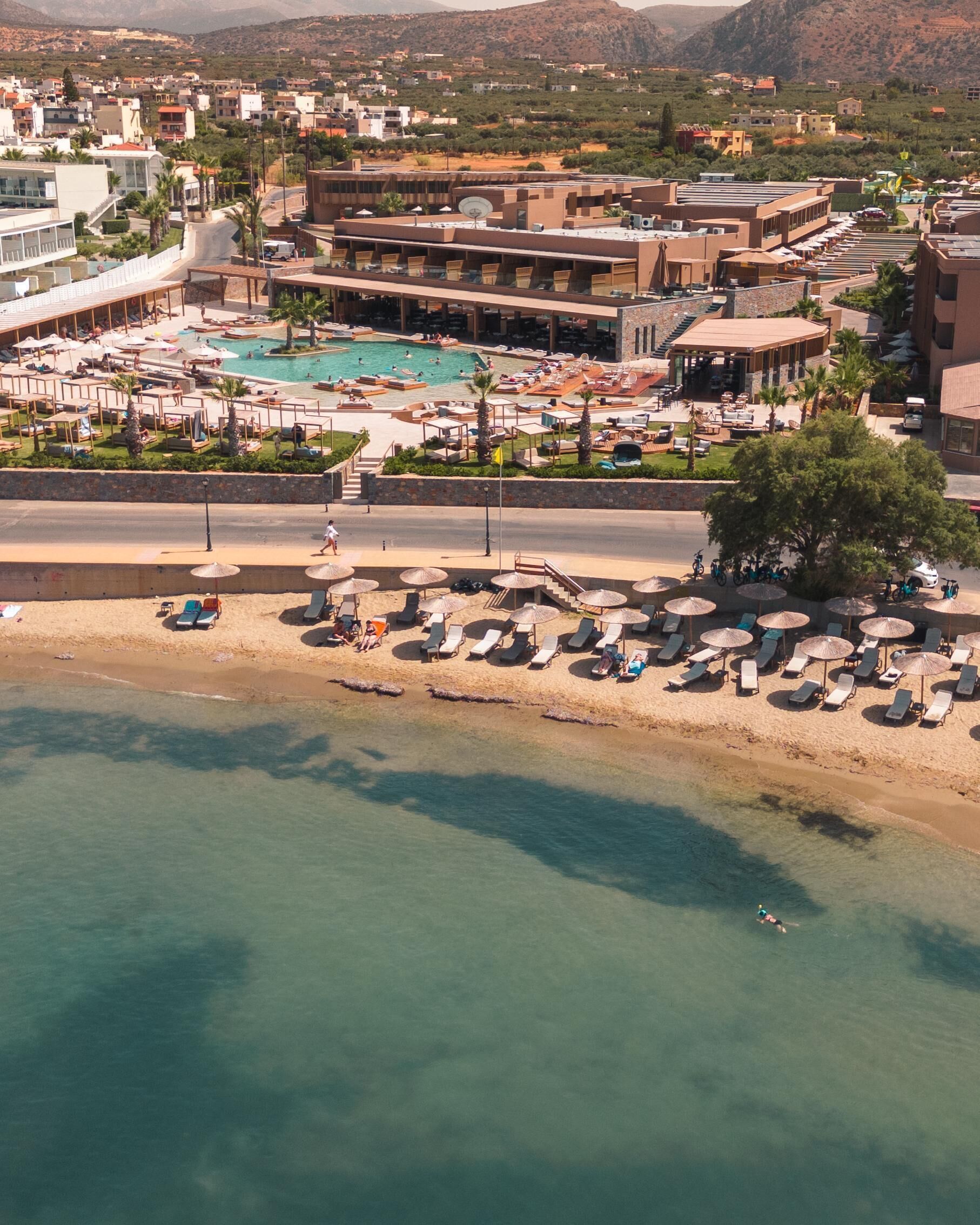 A resort with a swimming pool, beach area, and multiple buildings.