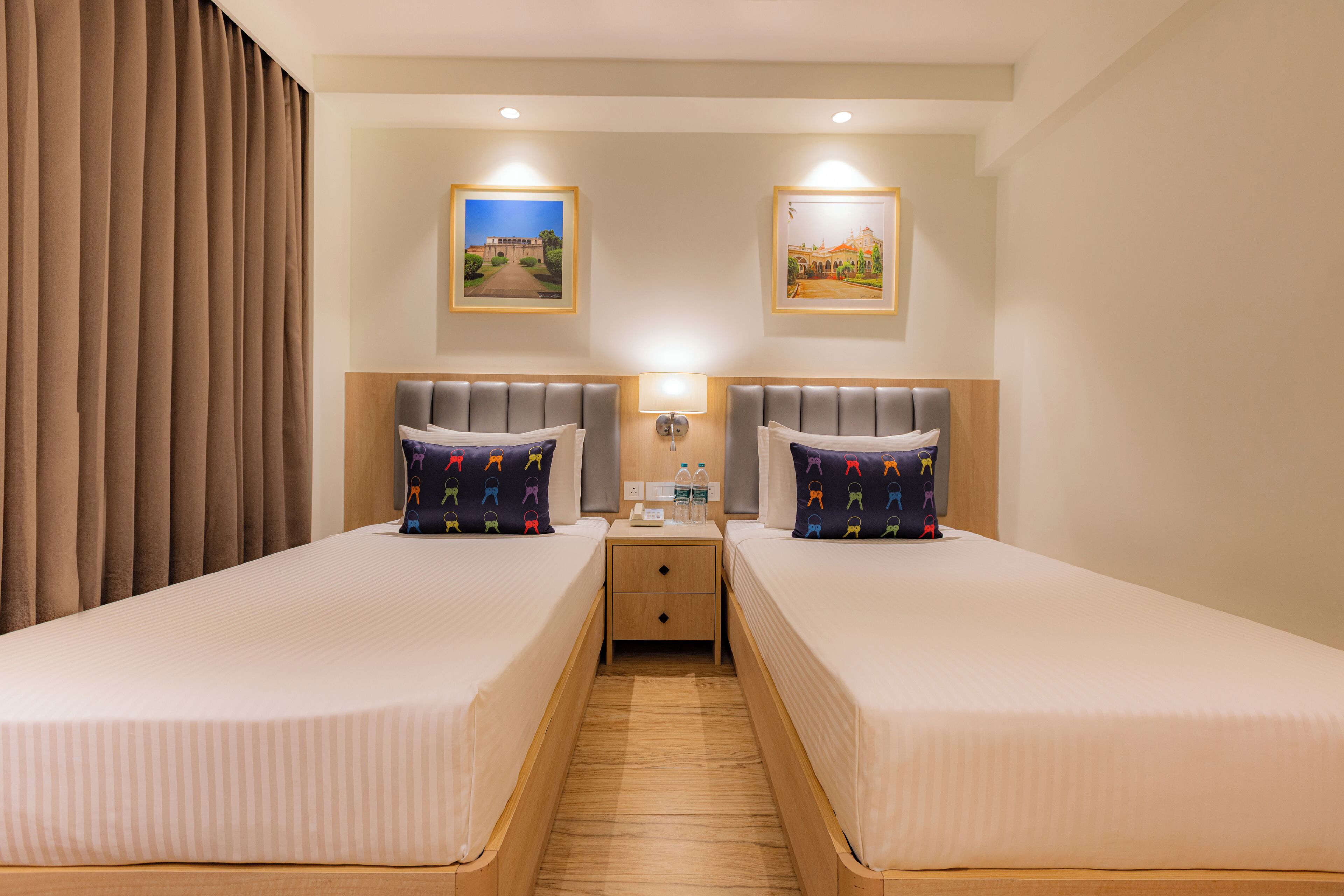 Una habitación de hotel con dos camas, una mesita de noche y una lámpara.
