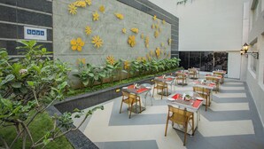 An outdoor dining area with tables and chairs, a decorative wall with yellow flowers, and a sign that reads "keys patio". - Keys Prima by Lemon Tree Hotels, Pimpri Pune (Pune)