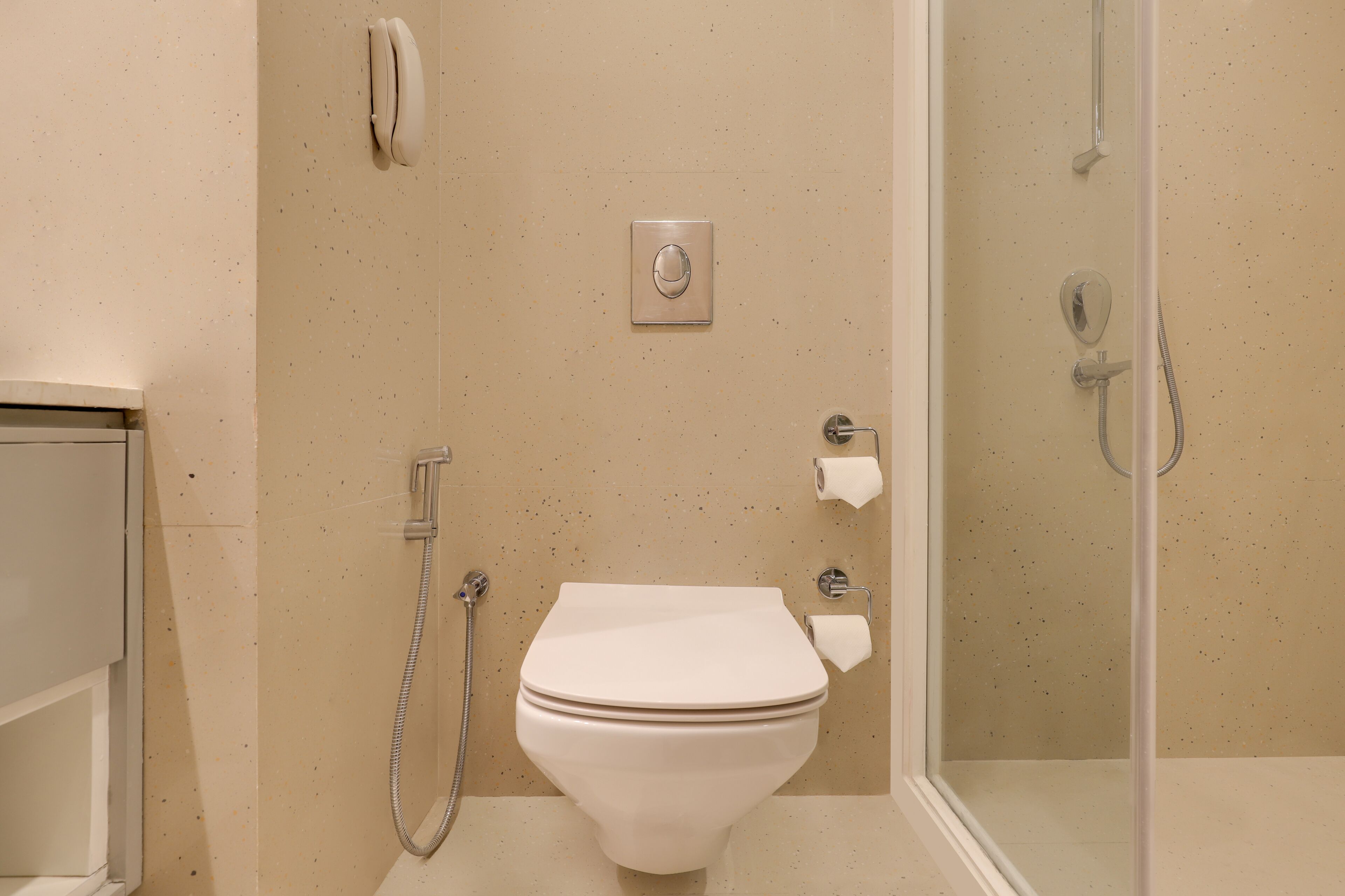 A bathroom with a toilet, a shower, and a toilet paper holder.