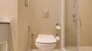 A bathroom with a toilet, a shower, and a toilet paper holder.