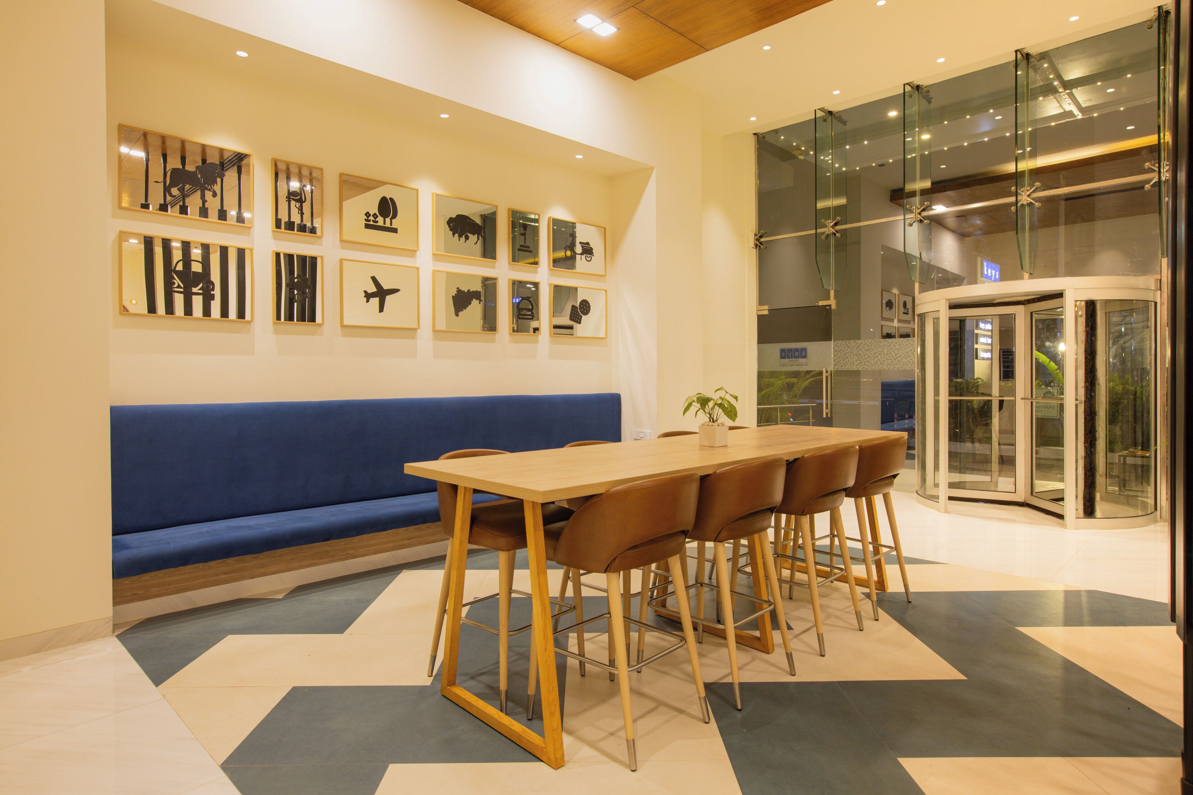 A modern interior with a wooden table, blue sofa, and framed pictures on the wall.