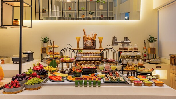 A buffet with various food items and drinks, including fruits, pastries, and a display of bread. - Keys Prima by Lemon Tree Hotels, Pimpri Pune (Pune)