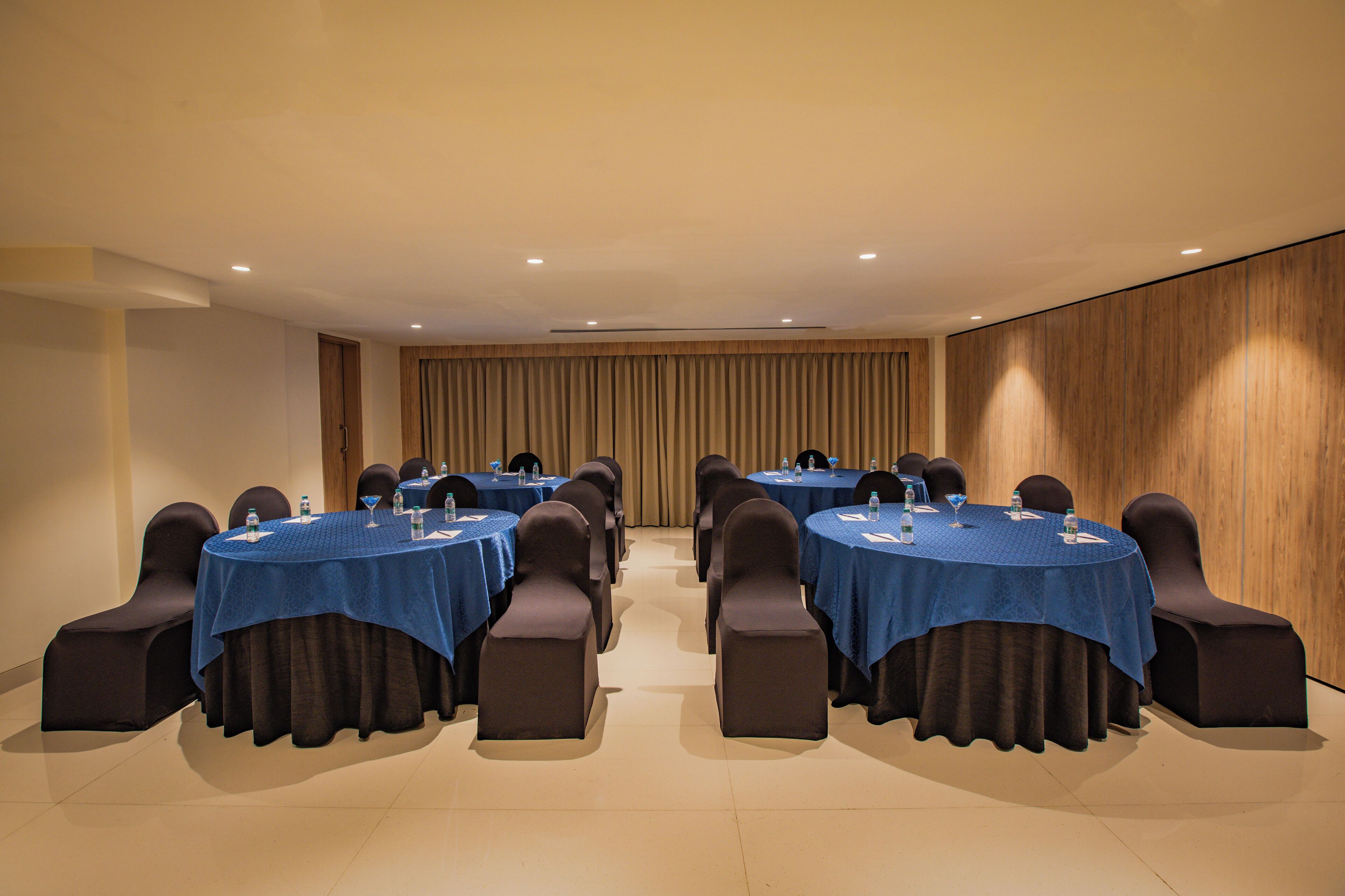A conference room with multiple tables and chairs, equipped with water bottles and glasses.