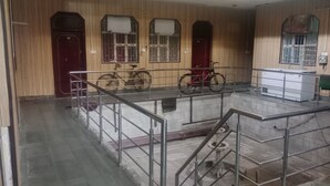 Una habitación amplia con una zona central que presenta un refrigerador blanco, una bicicleta y una puerta roja.