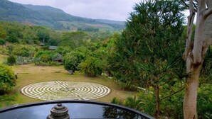 Un giardino con un motivo circolare in pietra, un lanterne in pietra e vista su un paesaggio montuoso.