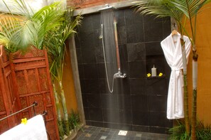 A shower area with a black tiled wall, a hanging white robe, and a wooden door. - Lakaz Chamarel Exclusive Lodge (Chamarel)