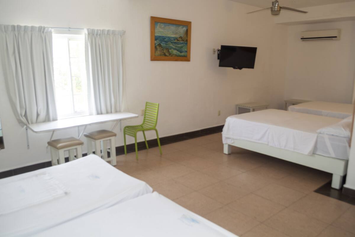Una habitación con dos camas, un escritorio, una silla, un televisor y un cuadro en la pared.