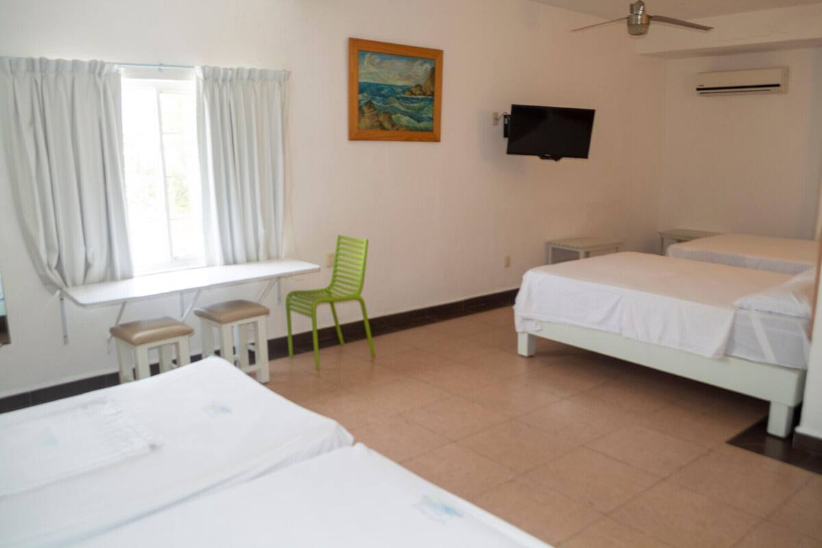 Una habitación de hotel con dos camas, un escritorio, una silla, un cuadro y un televisor.