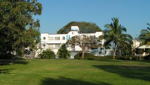 Un edificio grande y blanco con muchas ventanas y un letrero azul en el techo.
