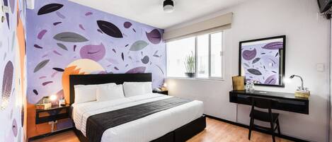 A modern bedroom with a bed, a desk, and a large window.